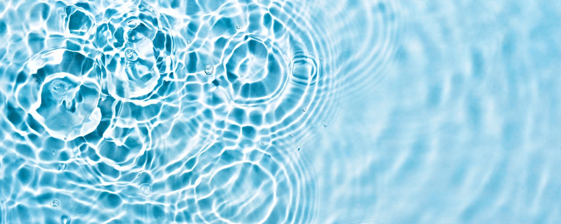 Close-up of light blue water surface with ripple patterns caused by falling droplets. Close-up of light blue water surface with ripple patterns caused by falling droplets.