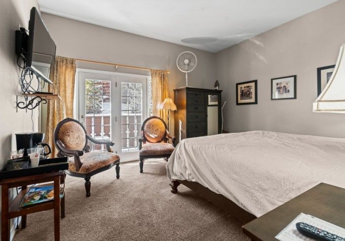 A bedroom with a bed , chairs , a table and a television.