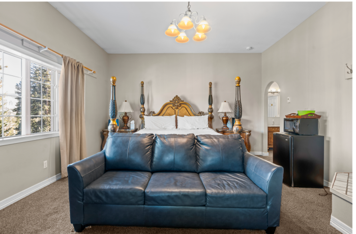 There is a couch in the middle of the room next to a bed.