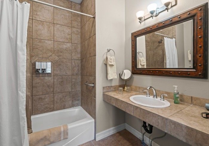 A bathroom with a sink , tub , shower and mirror.