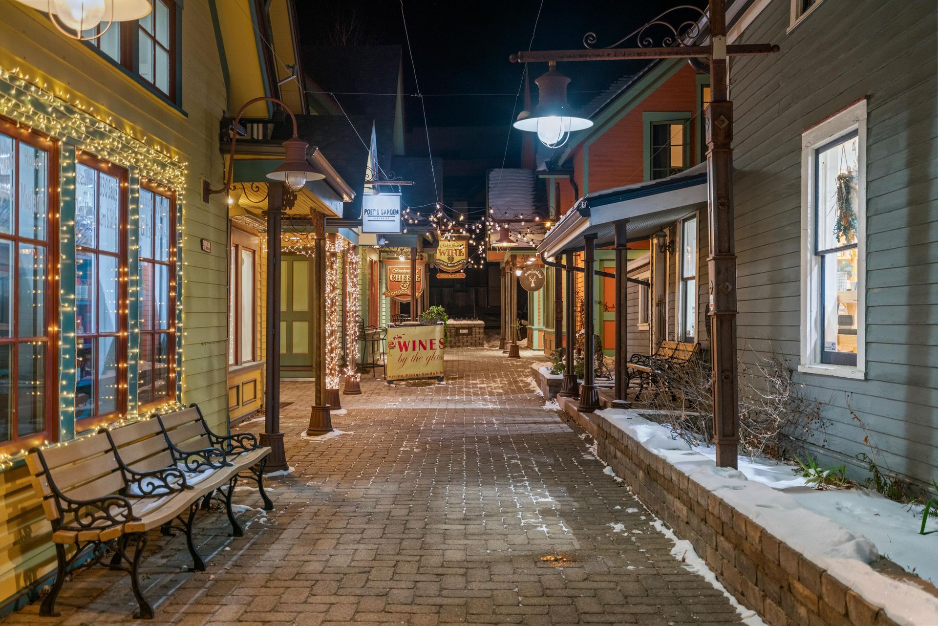 A narrow alleyway between two buildings at night with a bench in the middle.