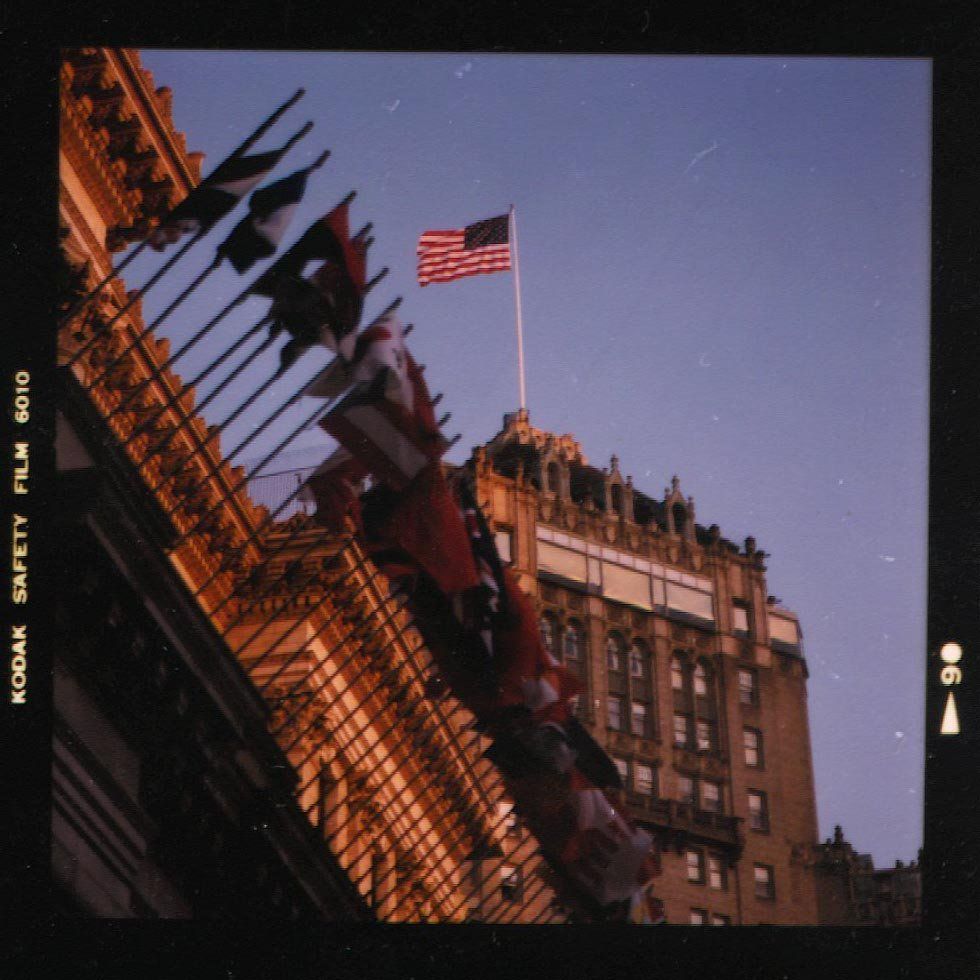 Building facade with American flag, other flags, and sunset sky.