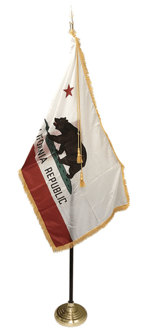 California state flag on a stand, white background. Features a brown bear, red star, and gold fringe.
