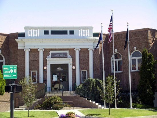 Brick building with white columns and flags. Sign: 