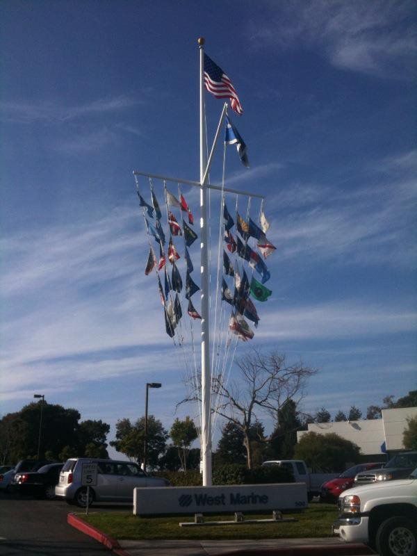 Flagpole with US flag and numerous smaller flags, over a sign that says 