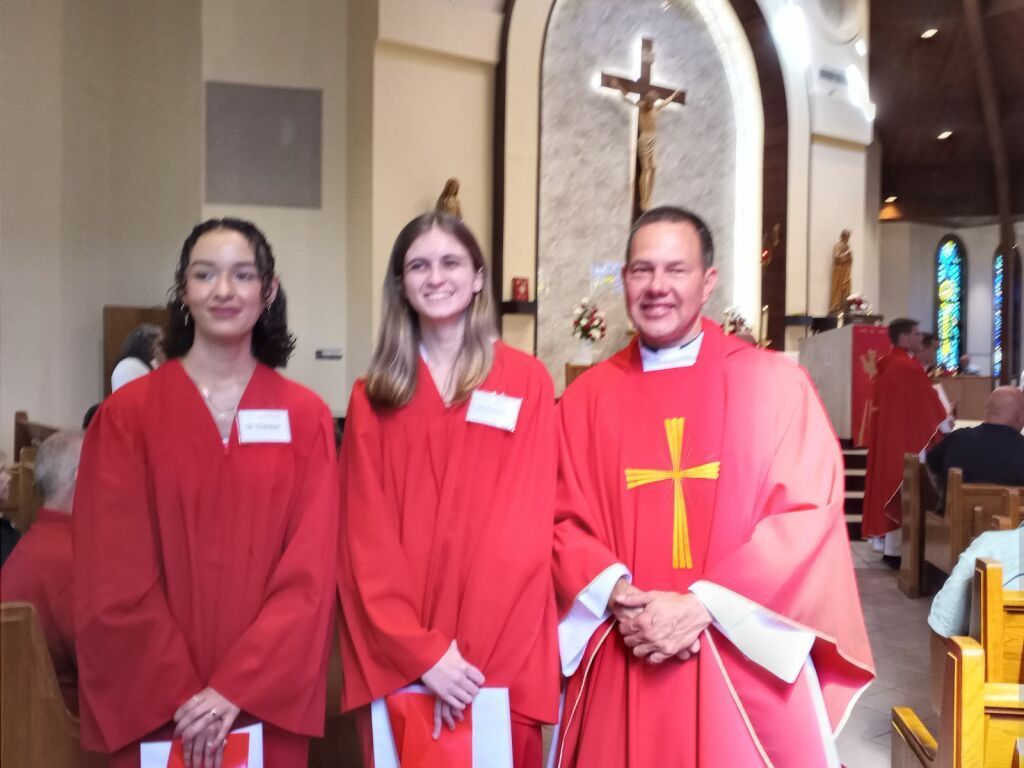 Three people in red church robes standing inside a church