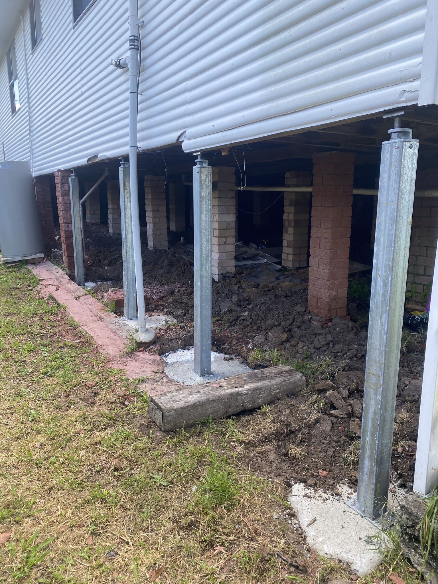 House With Damaged Piers Being Supported by Adjustable Steel Posts — Affordable Underpinning Solutions In Wollongong, NSW