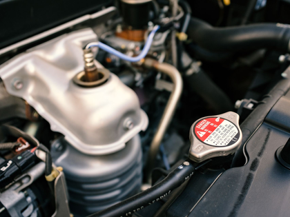 Close-up of a car engine bay with a metal strut mount and radiator cap