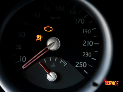 Car dashboard speedometer with warning lights illuminated and a service indicator.