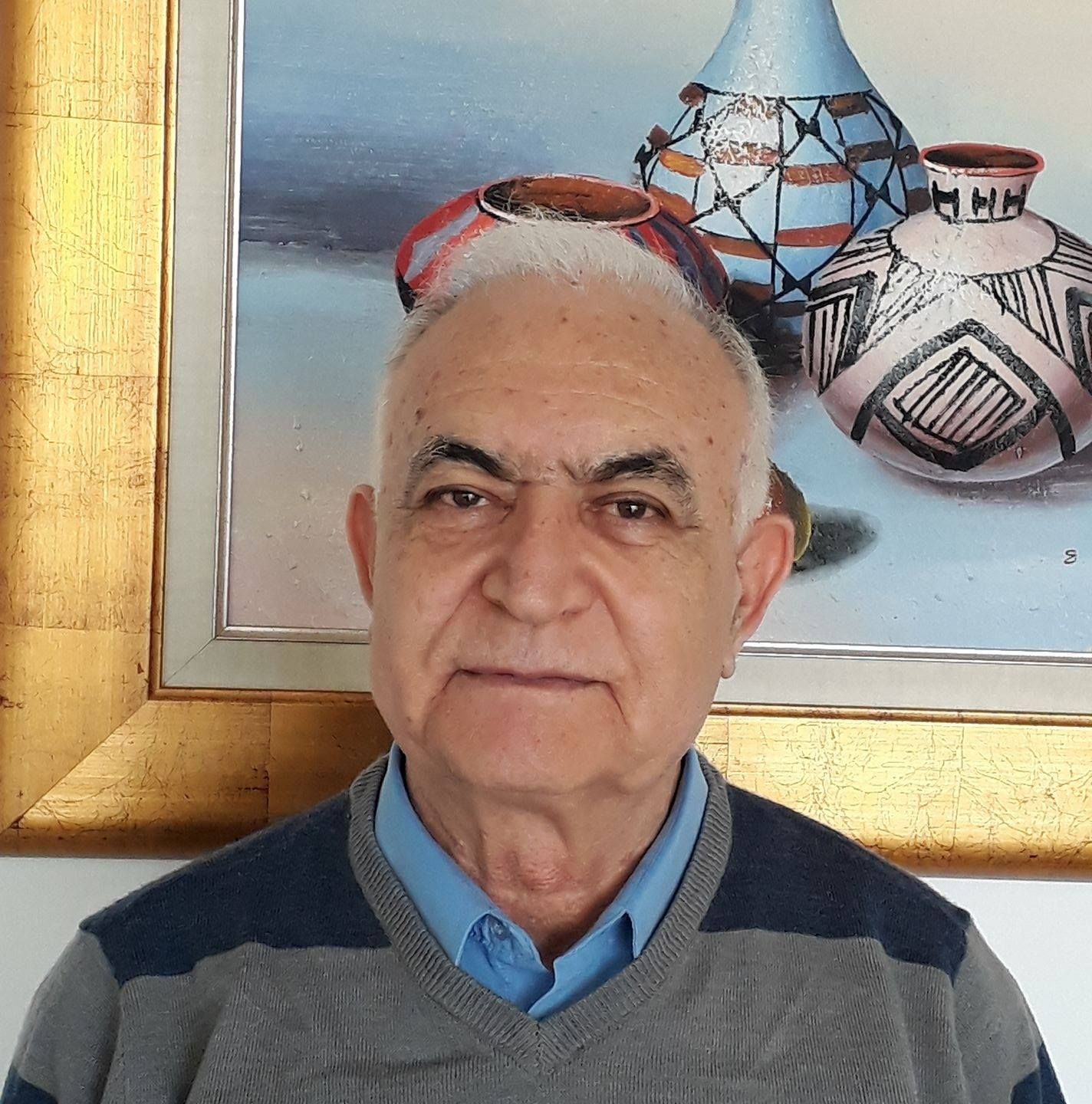 גבר קירח עם משקפיים מחייך, לובש חולצה שחורה עם צווארון וי.