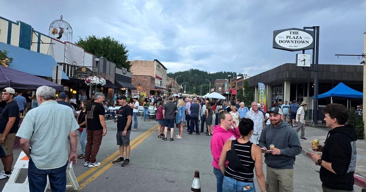 A crowd fills Main Street in downtown Bonners Ferry during Kootenai River Days, with the Georgia Mae Plaza sign and the brick storefronts behind