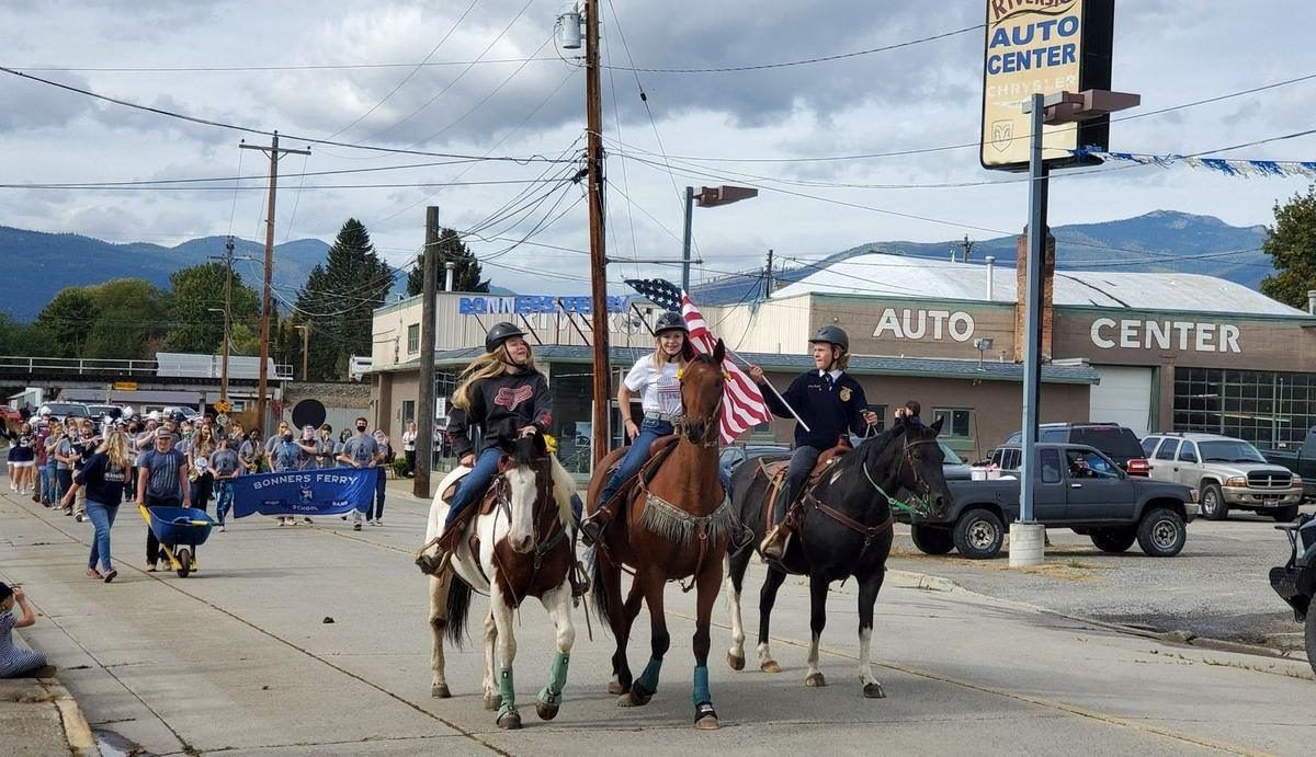 Three young riders on horseback carrying the flag lead the Bonners Ferry High School band down Main Street in a parade