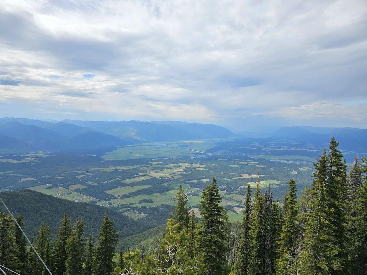 View from a Selkirk summit down the length of the Kootenai River valley under big clouds