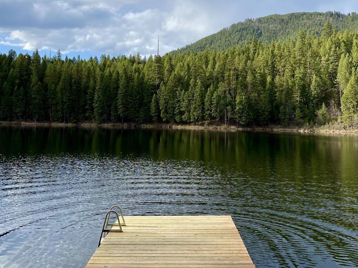 A wooden dock on Robinson Lake with forested hills under summer clouds