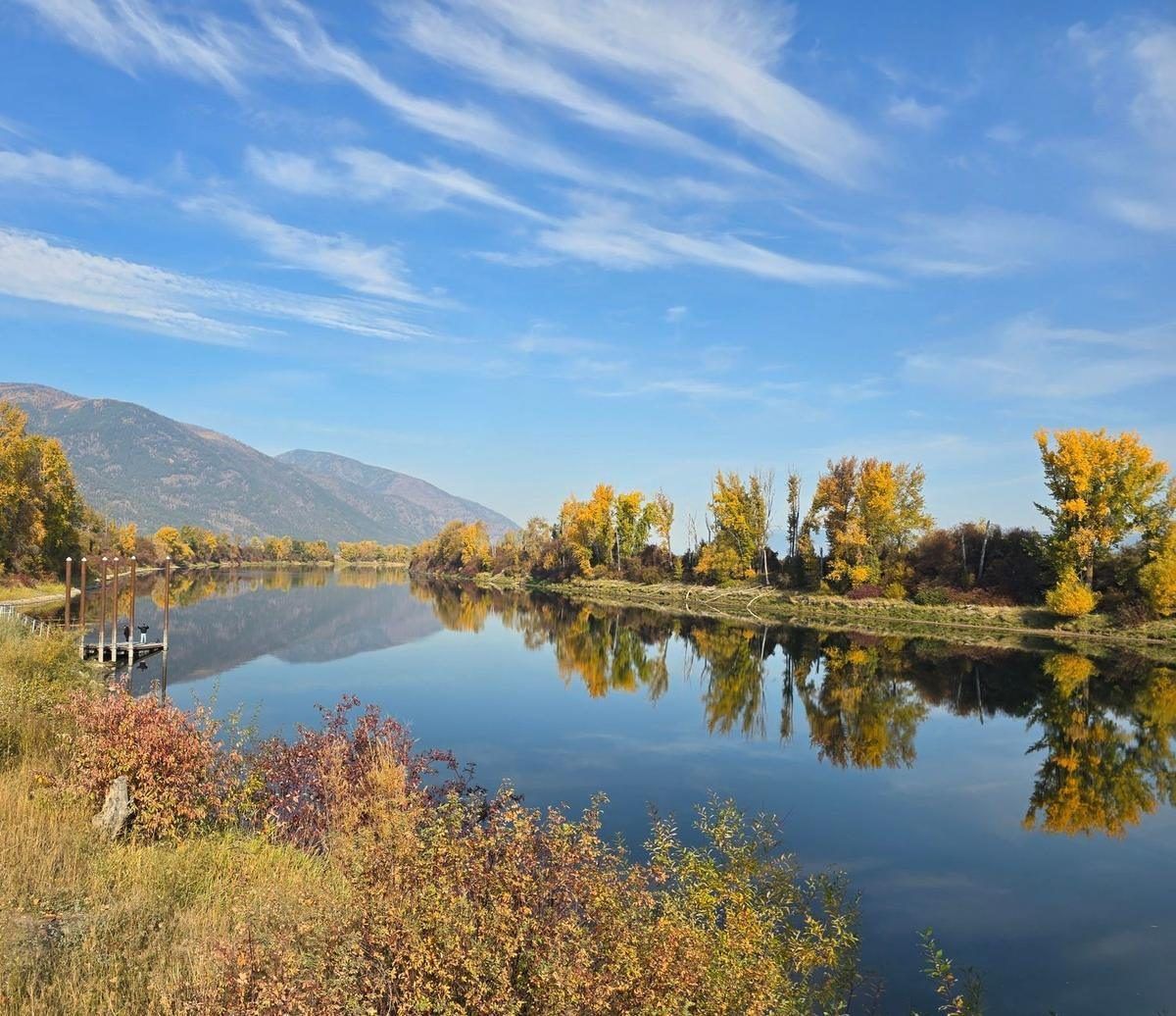 The mouth of Deep Creek at the Kootenai River, perfectly still in October, with gold cottonwoods and a small dock reflected in the water