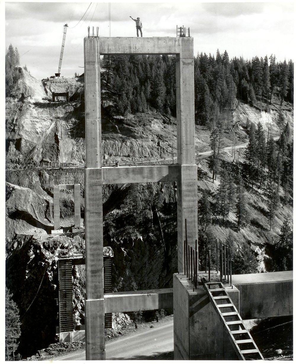 The concrete piers of the Moyie River Canyon Bridge under construction above the old highway, early 1960s