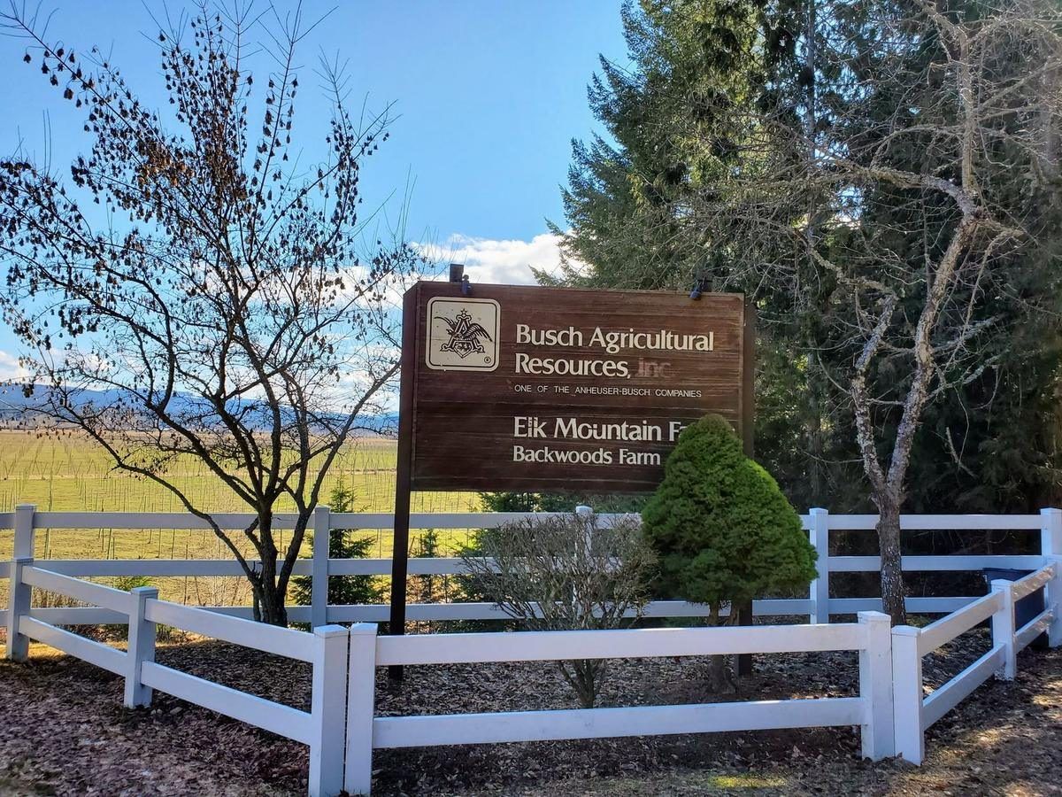 The Elk Mountain Farms entrance sign with a white fence and the valley behind