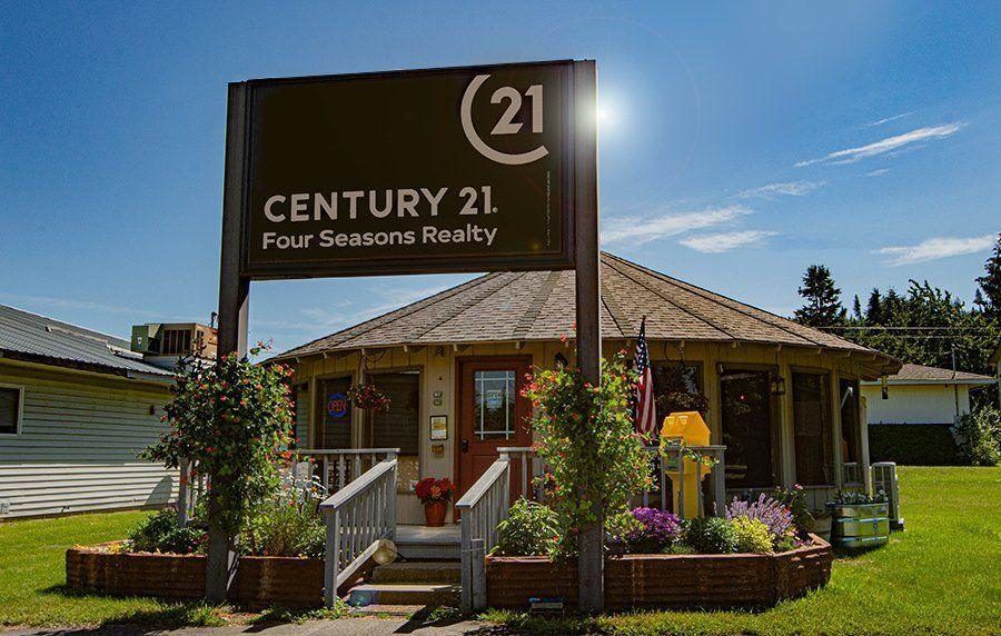 The round CENTURY 21 Four Seasons Realty office building in Bonners Ferry with its sign and flower beds
