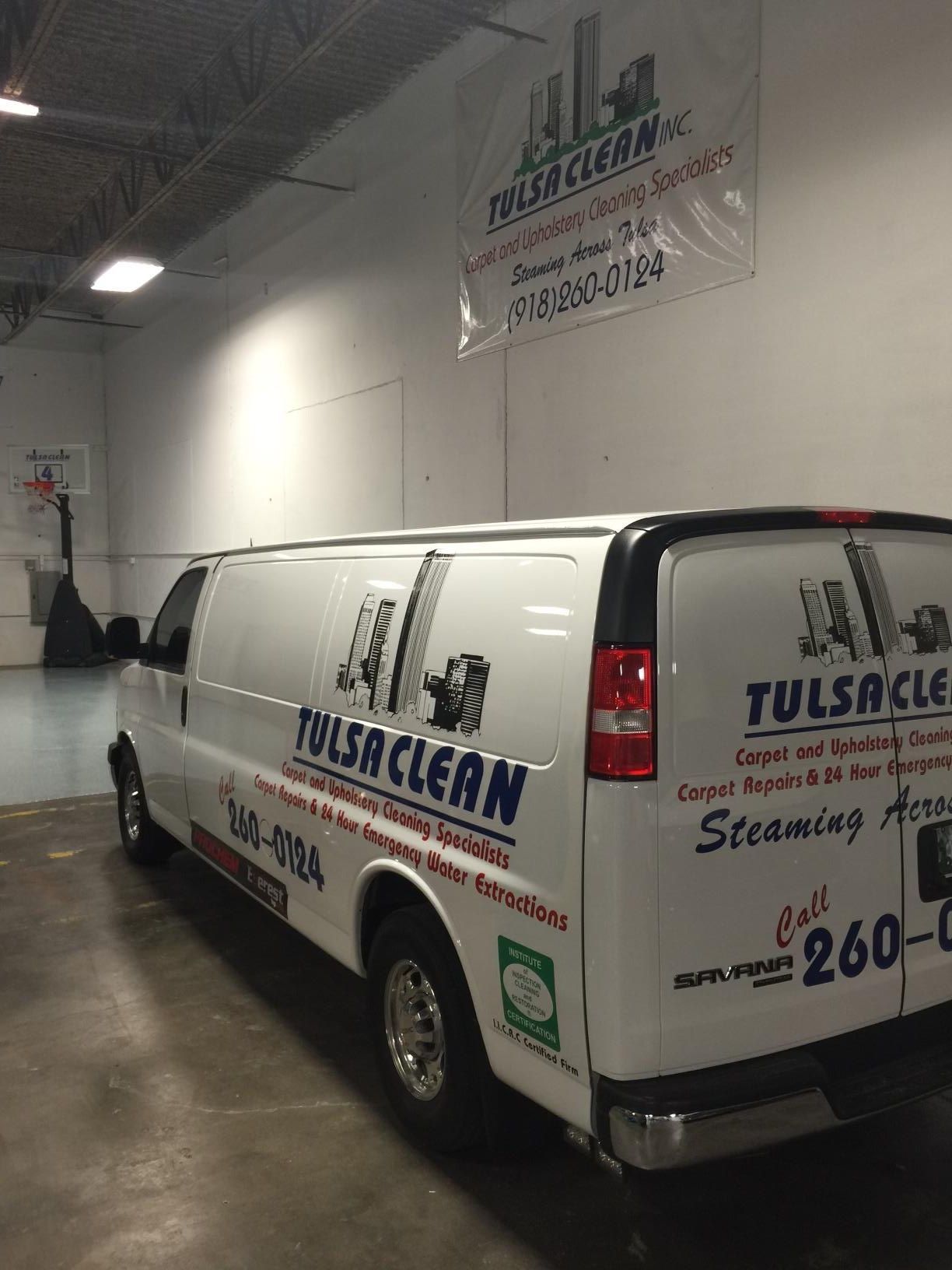 A white van with tulsa clean written on the side is parked in a garage.