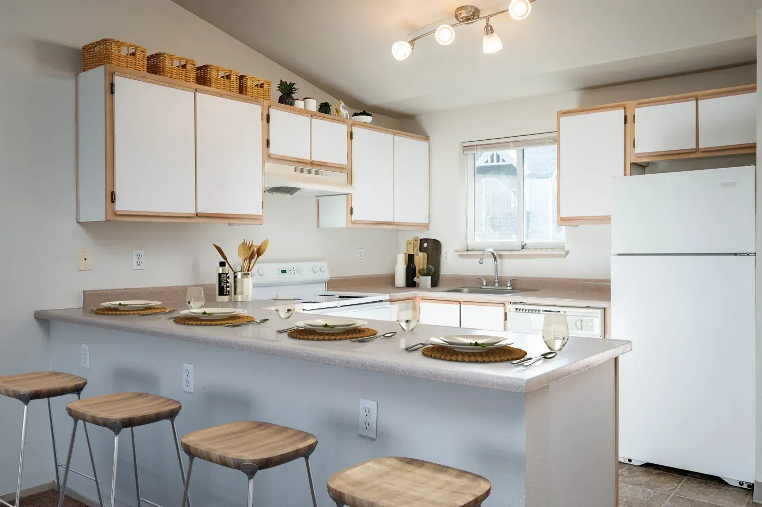 Kitchen with white cabinets, countertop bar with stools, and appliances.