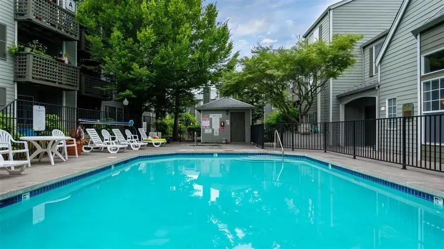 Swimming pool surrounded by apartments, with lounge chairs and a small pool house.