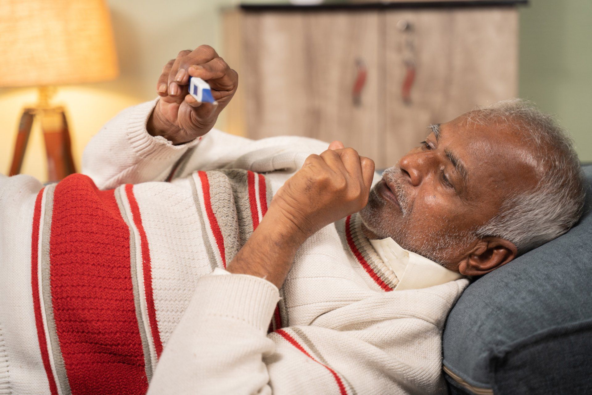 elderly man coughing and checking temperature