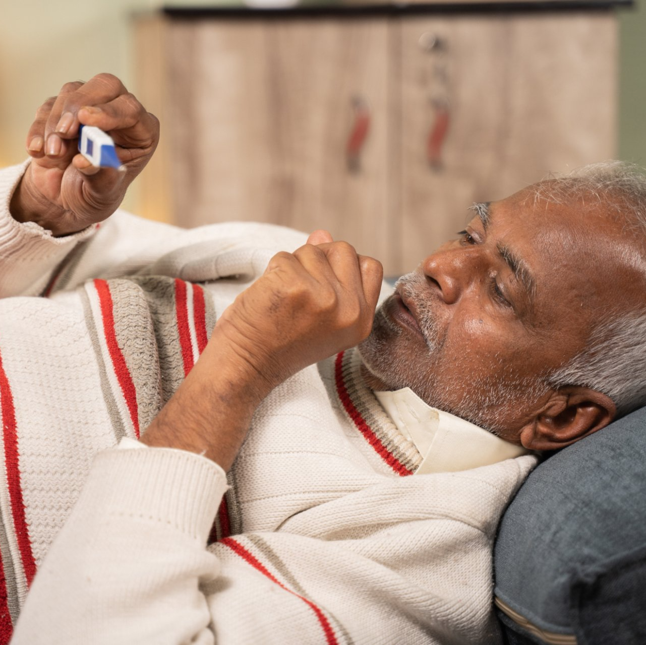 senior southeast asian man coughing and checking temperature