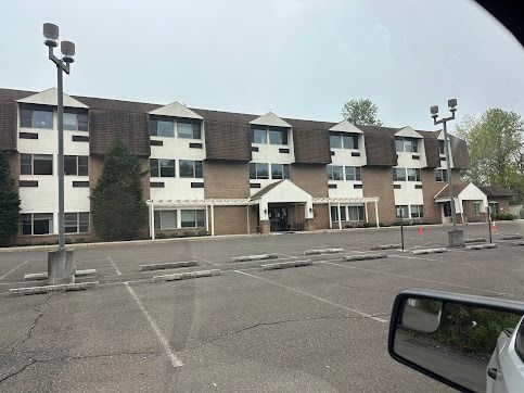 A multi-story brick building with a brown roof and a parking lot in front.