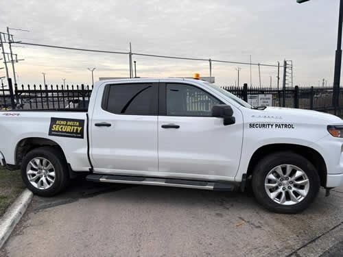 White security patrol truck parked outdoors with black and yellow logo.