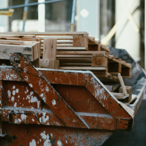 Rusty construction dumpster filled with stacked wooden planks at a worksite