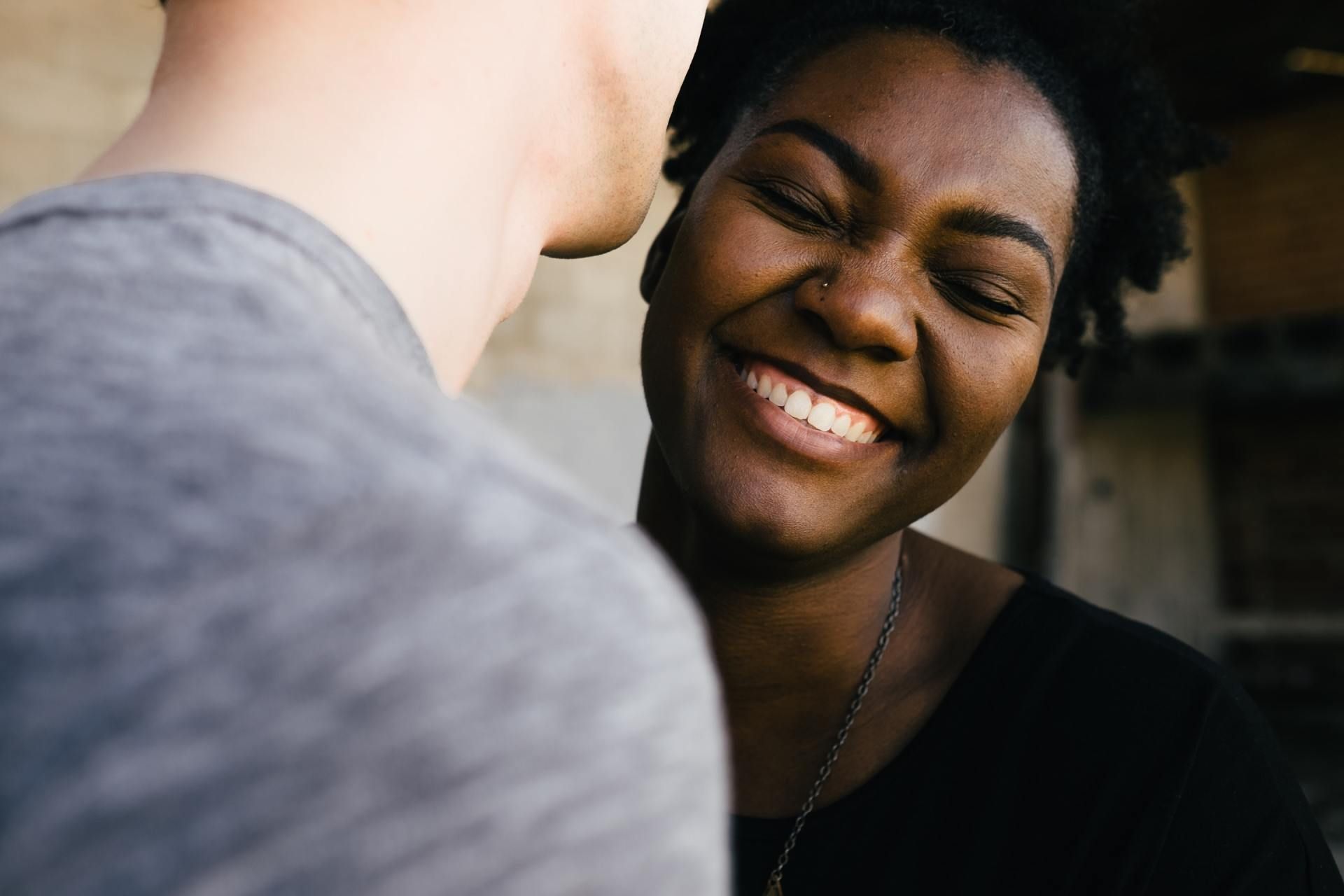 Woman smiles broadly while looking at someone off-camera.