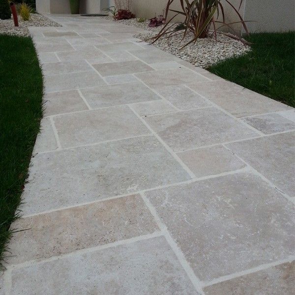 Stone walkway bordered by grass and desert plants in a landscaped yard
