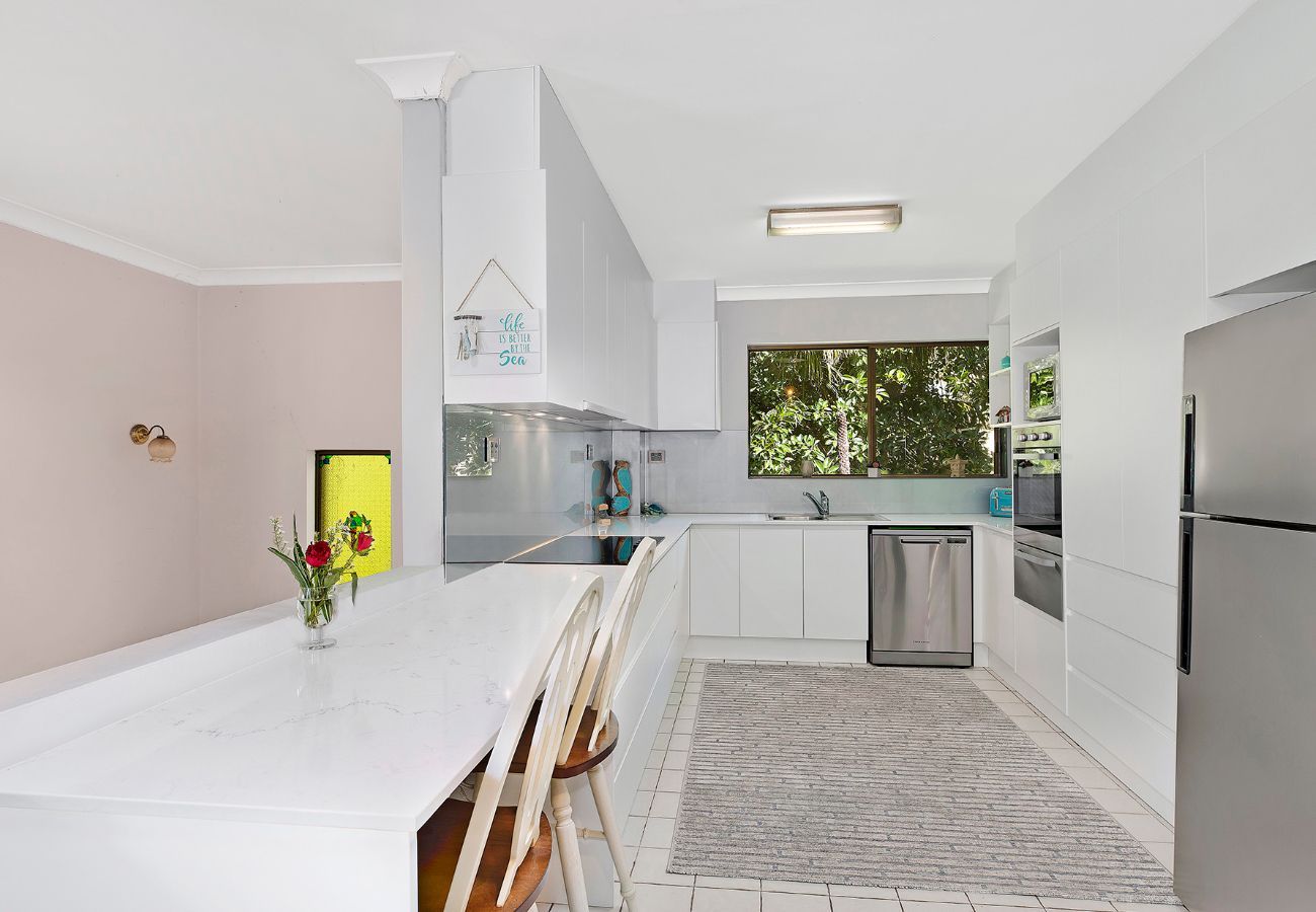 Kitchen With Island, Cabinets, Appliances, and a Window Overlooking Greenery — Affordable Tiles and Pavers In Morisset, NSW