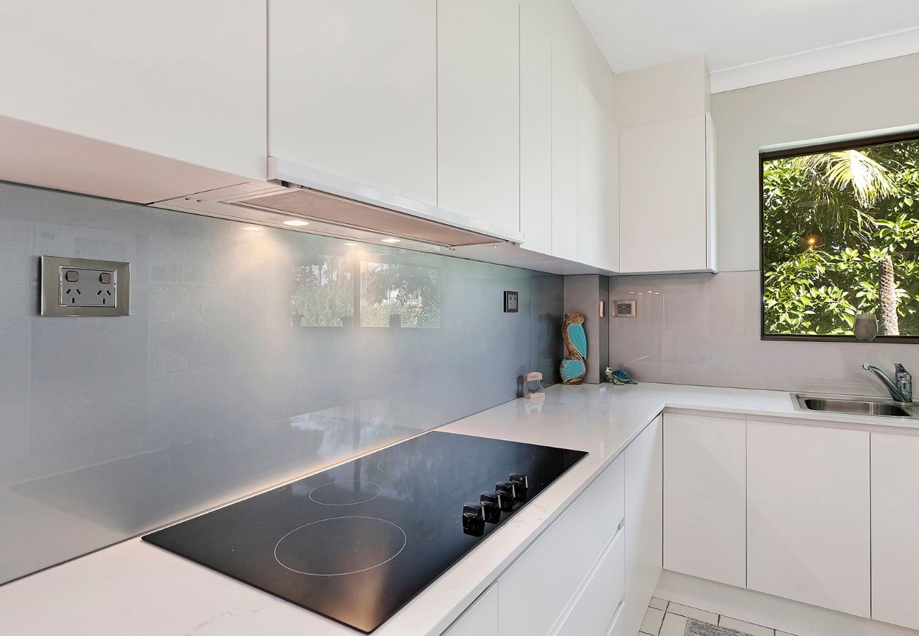 Modern White Kitchen With Cooktop, Light Blue Backsplash, and Window — Affordable Tiles and Pavers In Morisset, NSW