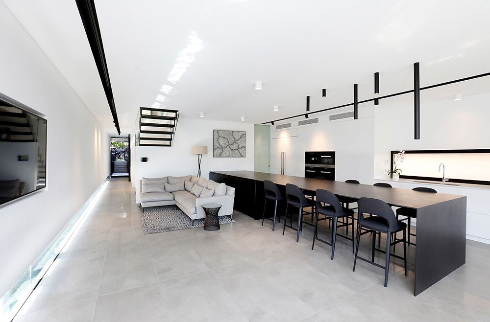 Modern Open-plan Kitchen and Living Area With Long Black Island, Black Chairs — Affordable Tiles and Pavers In Morisset, NSW