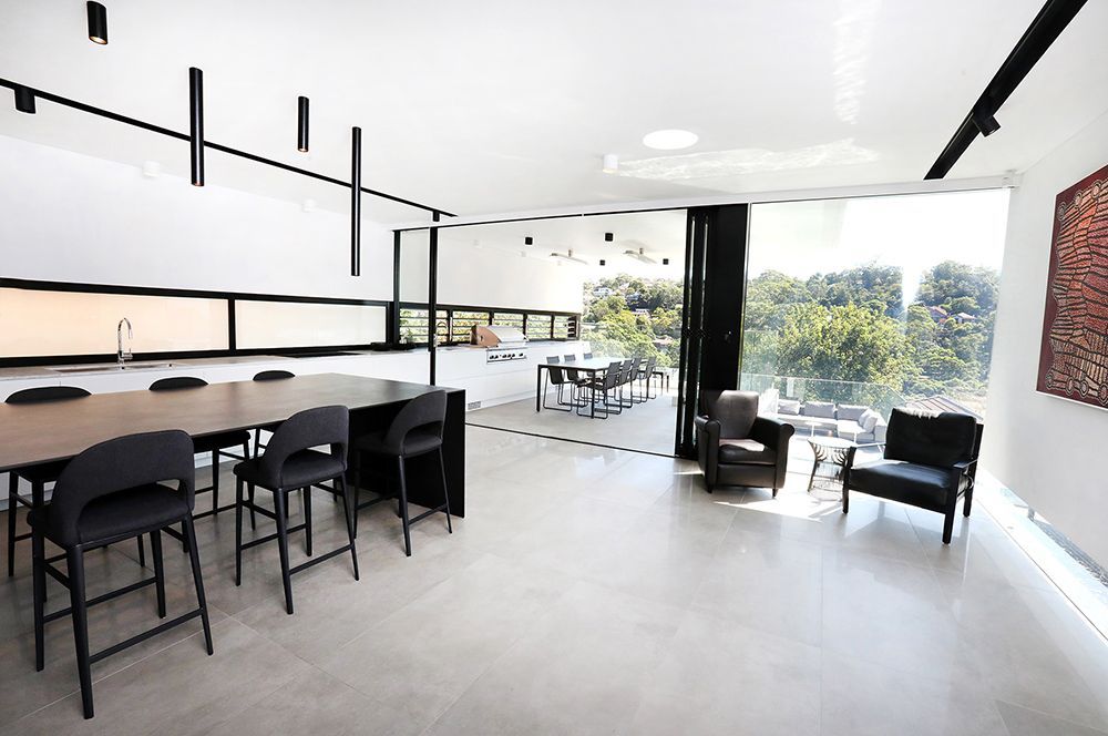 Modern, White-walled Room With Large Windows, Long Dark Table With Stools — Affordable Tiles and Pavers In Morisset, NSW