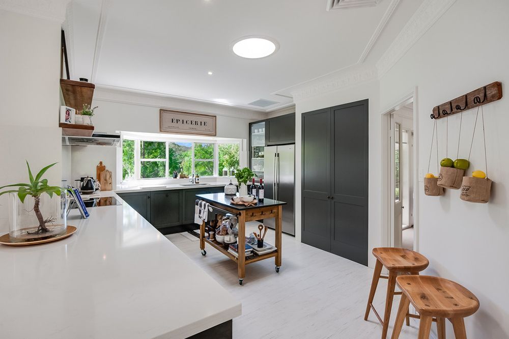 Kitchen With White Counters, Dark Green Cabinets, and Wooden Island — Affordable Tiles and Pavers In Morisset, NSW