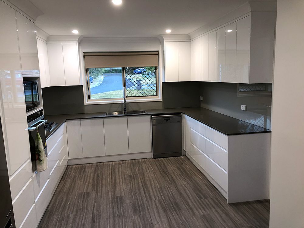 Modern White Kitchen With Dark Countertops, Stainless Steel Appliances — Affordable Tiles and Pavers In Morisset, NSW