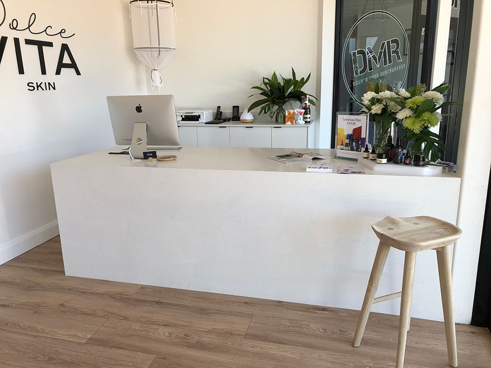White Reception Desk in a Skincare Clinic With , Flowers, and a Stool — Affordable Tiles and Pavers In Morisset, NSW