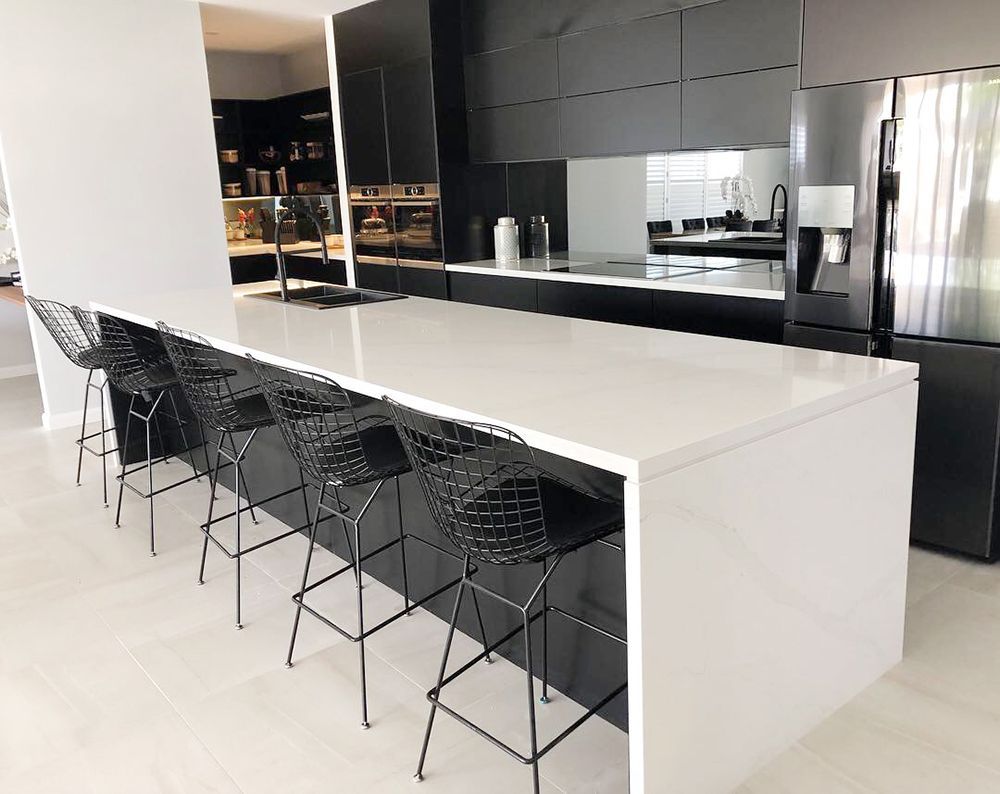 Modern Kitchen With Black Cabinetry, White Countertops, and Bar Stools — Affordable Tiles and Pavers In Morisset, NSW