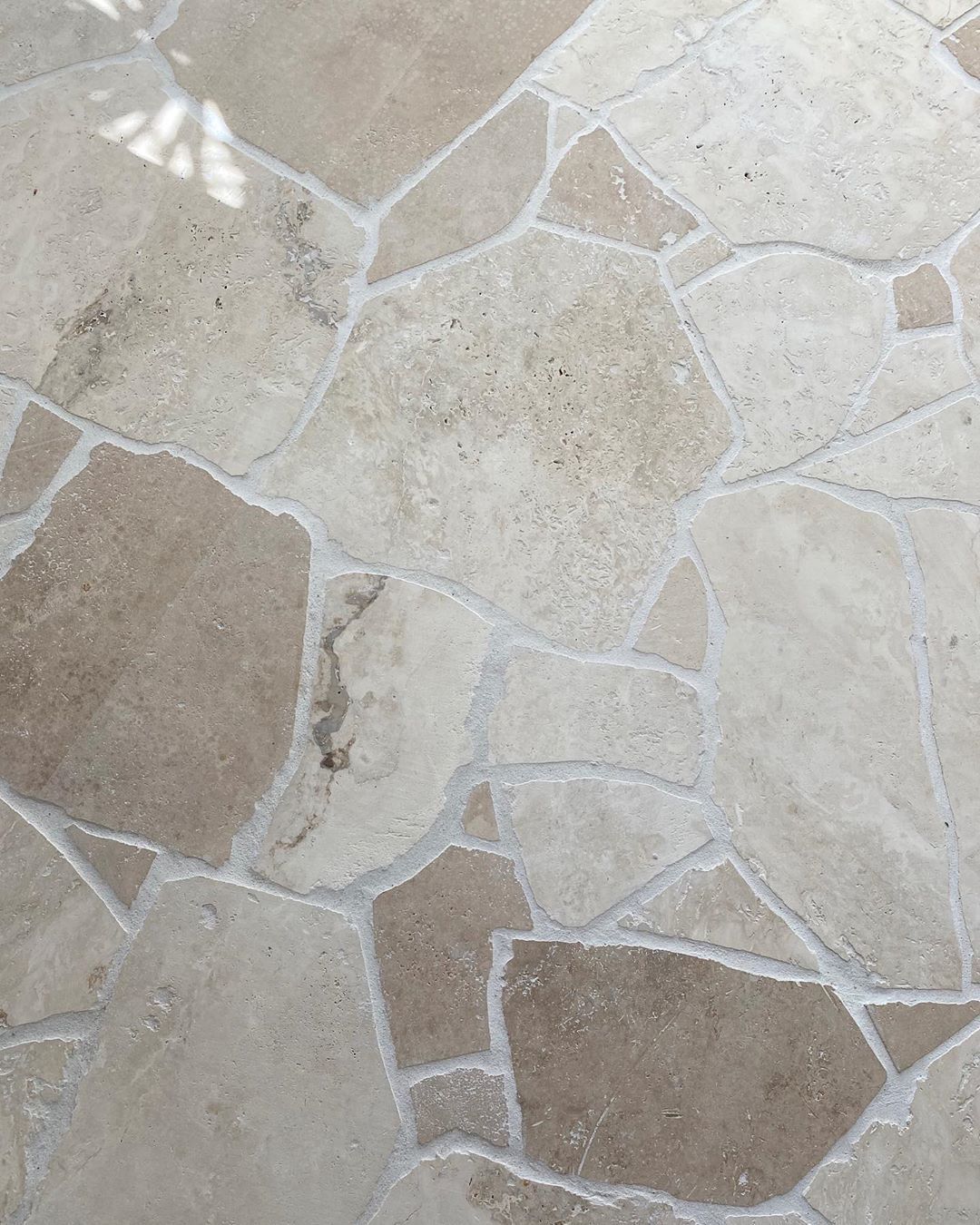 Beige stone patio with irregular flagstone tiles and light grout lines