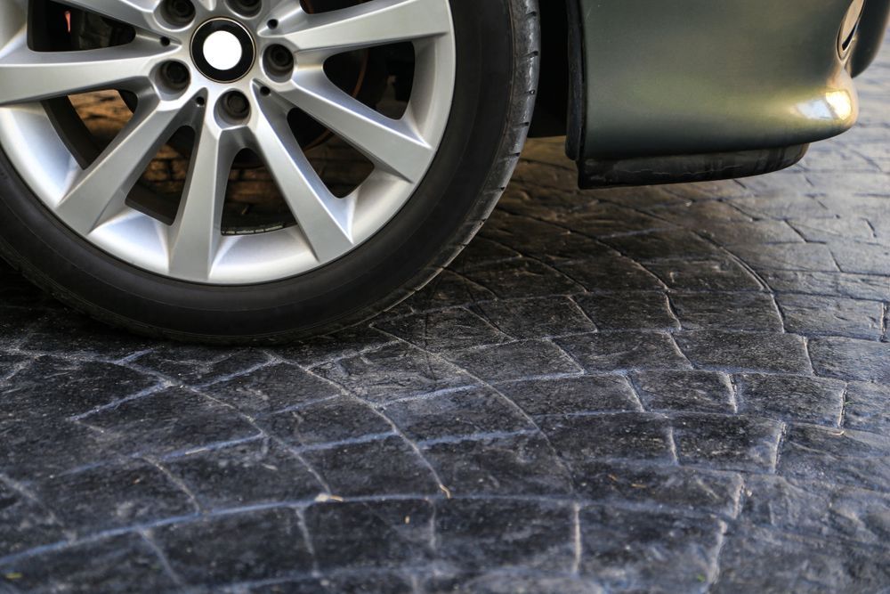 Car Tire on Textured Dark Gray Pavement — Affordable Tiles and Pavers In Morisset, NSW