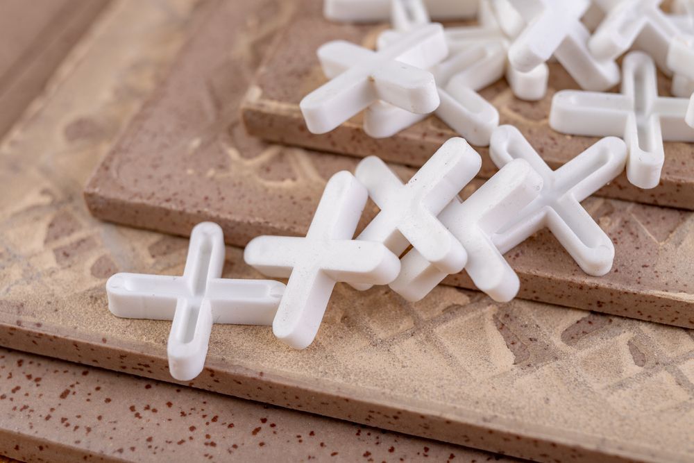 White Plastic Tile Spacers on Brown Tiles — Affordable Tiles and Pavers In Morisset, NSW