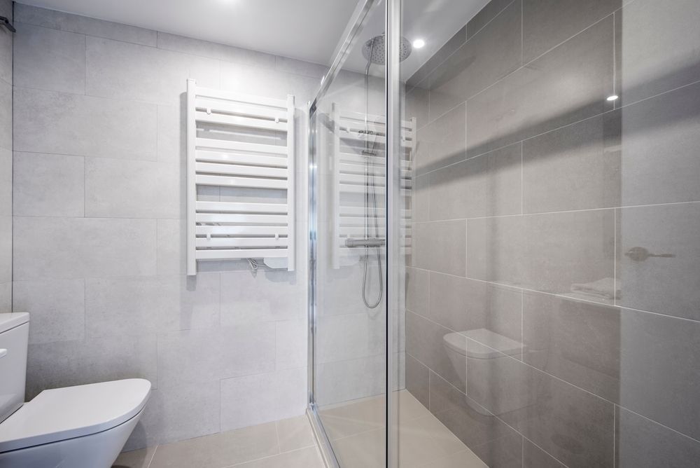 Modern Bathroom With Glass Shower, Heated Towel Rack, and Toilet — Affordable Tiles and Pavers In Newcastle, NSW
