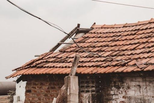 Damaged clay tile roof on an old house showing missing and broken roofing tiles needing repair.