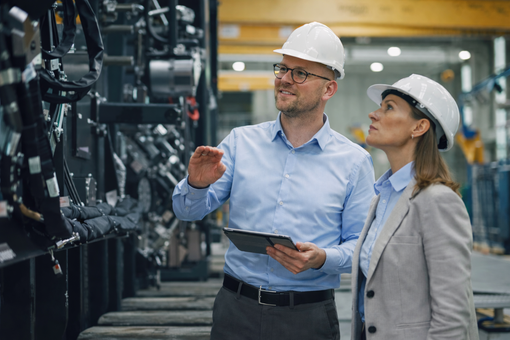 Twee ingenieurs met veiligheidshelmen inspecteren apparatuur in een industriële installatie.