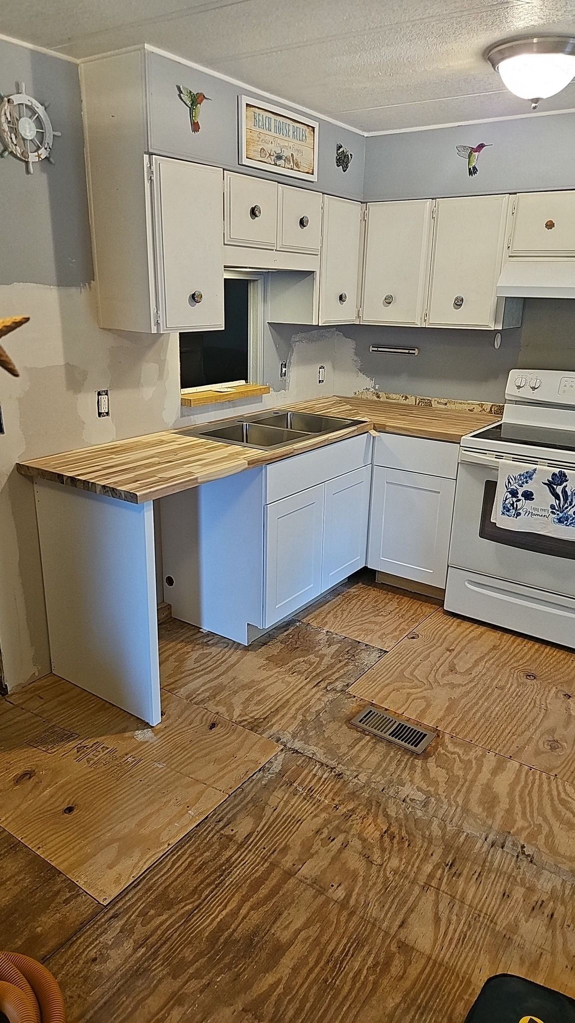 Damaged kitchen with scattered debris, missing cabinets, and stained countertops and floor