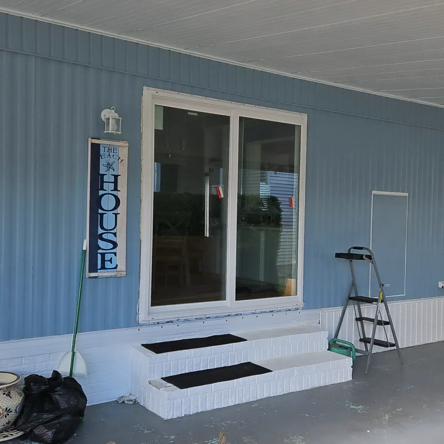 Blue storefront with glass double doors, white steps, and a vertical