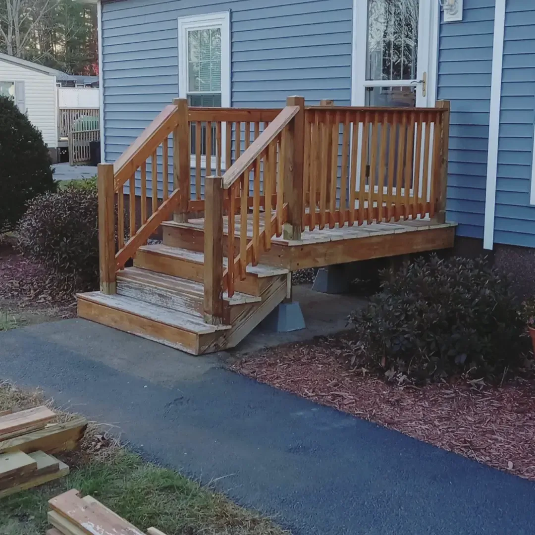 Wooden accessibility ramp with railings leading to a blue house entrance