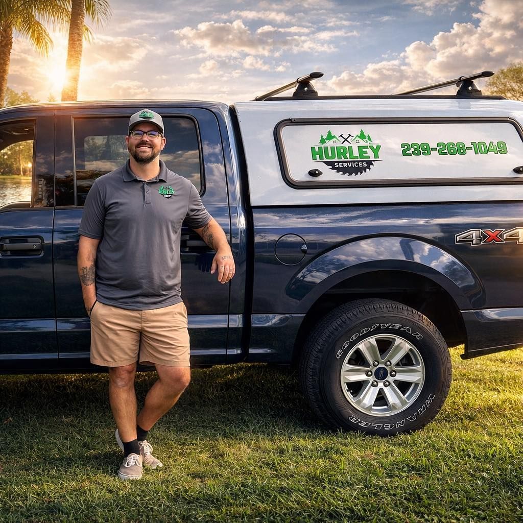 Man standing beside a blue pickup truck with a Huxley service logo at sunset.